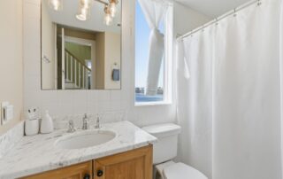 Bright bathroom with marble sink, wooden cabinet, and large window with ocean view, ideal for Southport rentals.