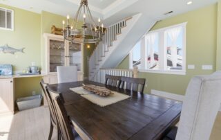 Elegant dining area with wooden table, chandelier, and window lighting, perfect for Southport rentals showcasing charm and style.