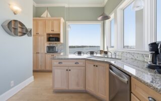 Bright kitchen with light wood cabinets, granite countertops, scenic ocean view. Perfect for Southport rentals seeking coastal charm and modern amenit