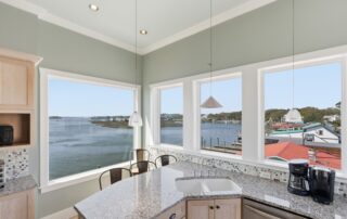 Bright kitchen with granite countertops overlooks a serene waterway through large windows, highlighting views of Southport rentals and boats.