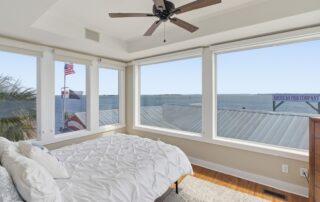 Bright bedroom with ocean view, ceiling fan, and American flags, ideal for Southport rentals.