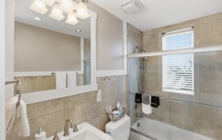 Modern bathroom with beige tile, glass shower door, and white sink, ideal for Southport rentals.