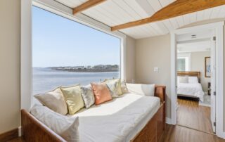 Cozy room with wooden daybed, pillows, and ocean view, leading to a bedroom; ideal for Southport rentals.