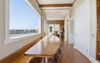 Spacious kitchen-dining area in Southport rentals, featuring wooden furniture, large waterfront window, and hardwood floors.
