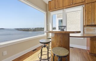 Bright kitchen with wooden island and stools, large window offering a scenic waterfront view, perfect for experiencing Southport rentals.