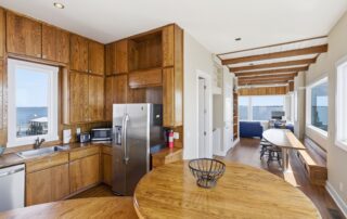 Spacious kitchen with wood cabinets, stainless appliances, ocean view, and adjacent seating area ideal for Southport rentals.