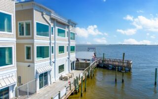 Coastal building beside a wooden pier extending into a sunny, calm sea. Perfect for Southport rentals with waterfront views.
