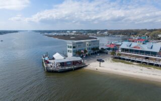Aerial view of waterfront buildings in Southport, North Carolina with docks and boats, showcasing potential Southport rentals near the river.